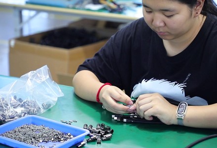 Operator assembling metal connector pins and shells at a bench