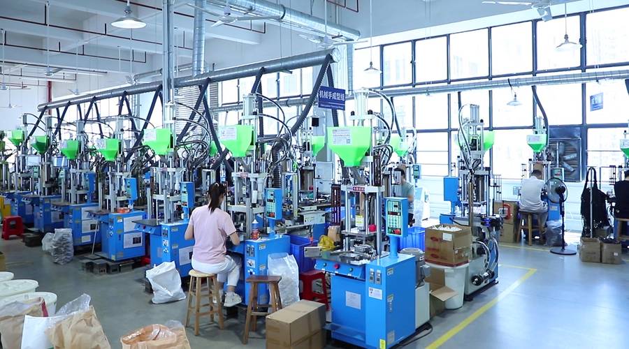 Row of vertical injection moulding machines overmoulding cable connectors